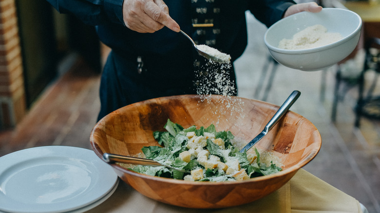 waiter sprinkling cheese on Caesar salad