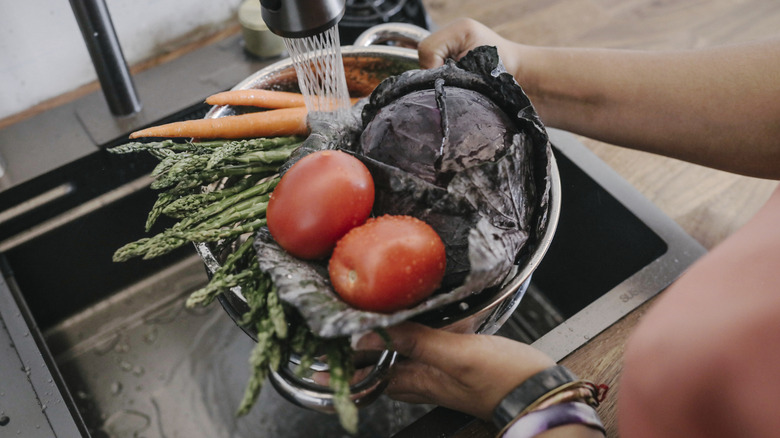 Rinsing a colander of veggies in the sink