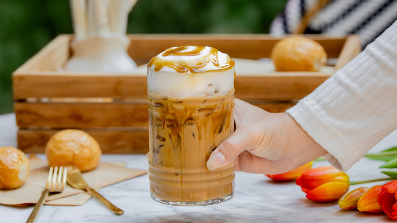 Person holding a glass of iced latte