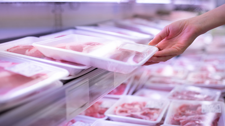 Hand holding packaged pork at grocery store