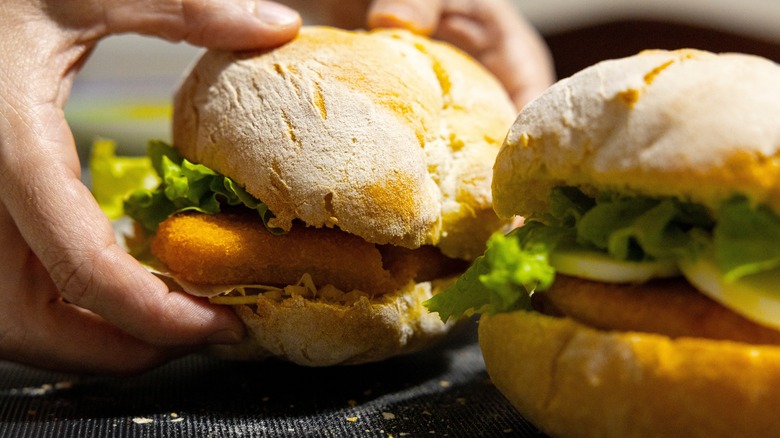 Person holding a fish sandwich on a crusty roll