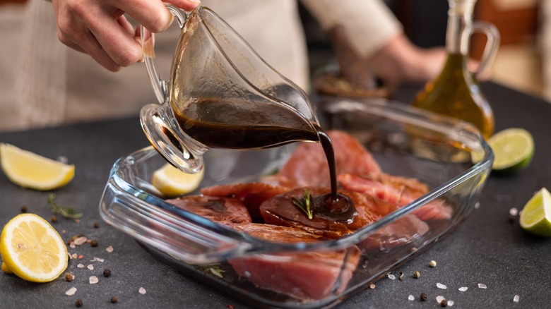 Person pouring marinade on fish