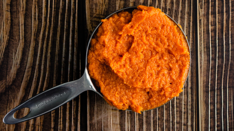 Measuring cup of canned pumpkin puree