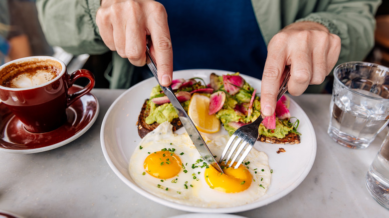 A person cuts into fried eggs at a restaurant