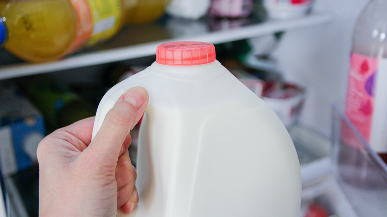 Hand pulling milk out of fridge