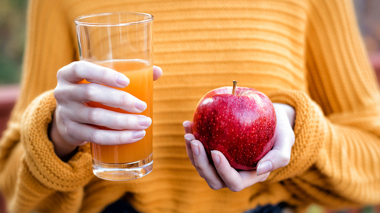 woman holding cider and apple