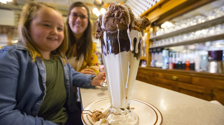 A woman and a child next to a Tin Roof sundae