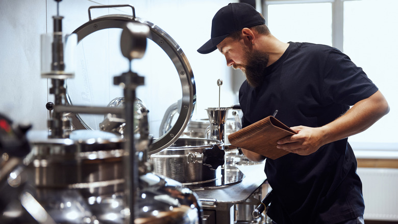 A bearded man tending to beer being brewed