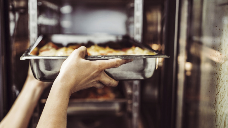 Person placing baking tray into a professional convection oven