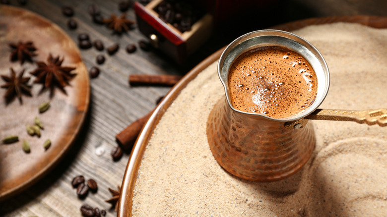 Turkish coffee cooking on sand with spices on plate and table