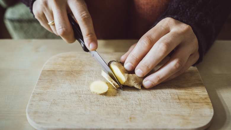 Slicing ginger root on a cutting board