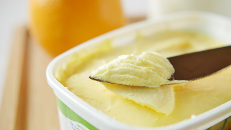 knife going through tub of margarine