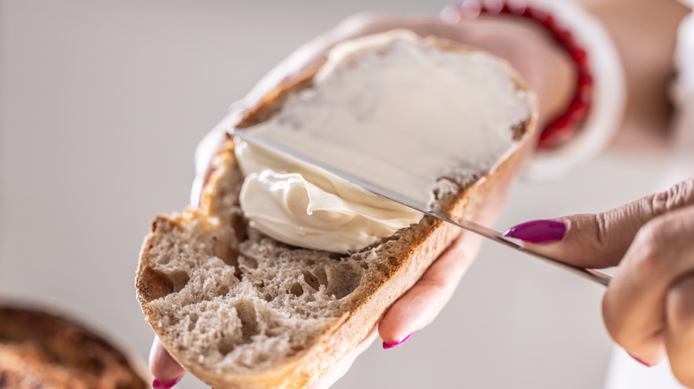 hand spreading butter on toast