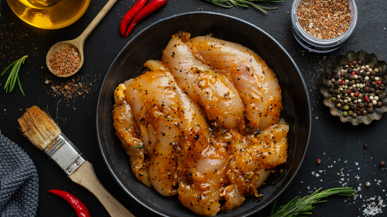 Chicken breasts rest in a spice marinade.