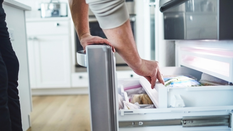 person reaching in freezer