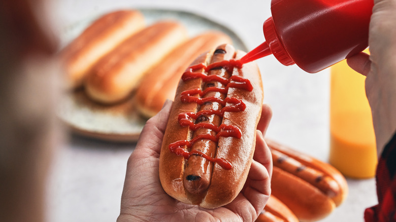 Squeezing ketchup on hot dog