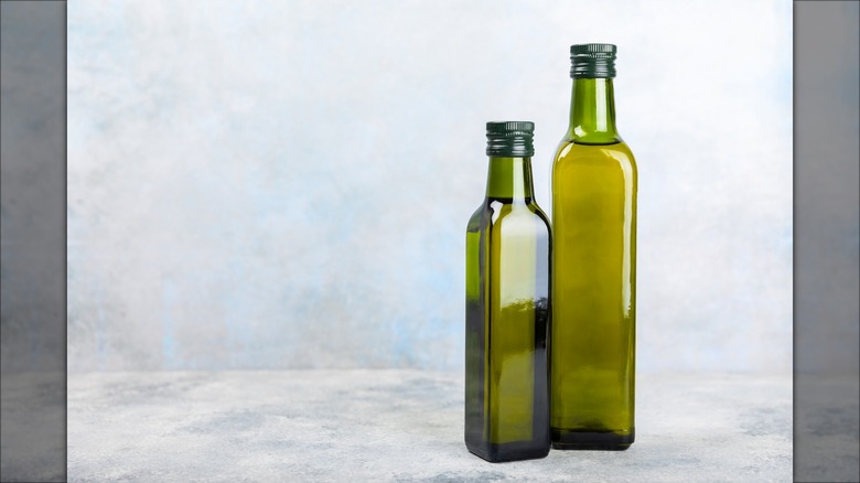 two green olive oil bottles on a counter