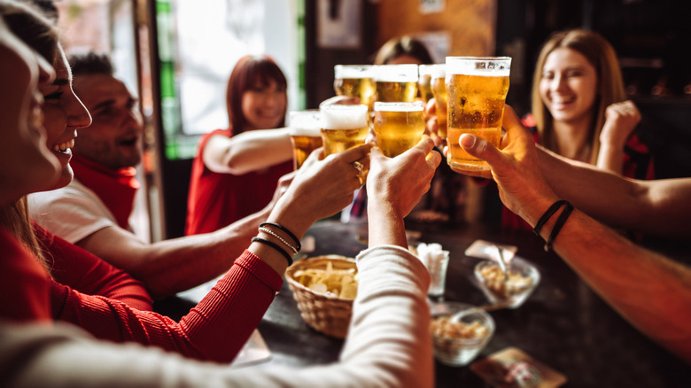 Friends toast beers at a bar