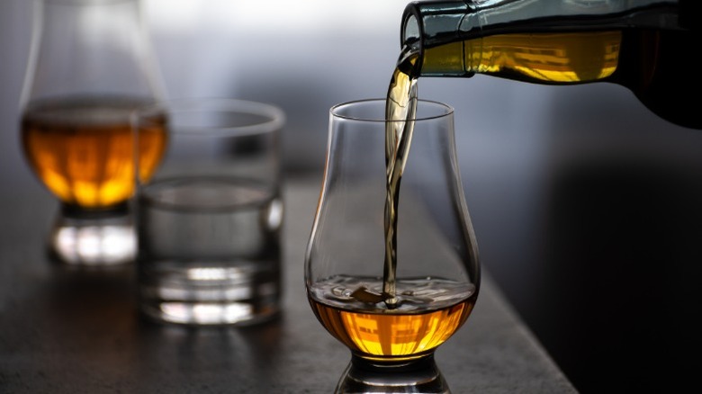 Whiskey poured into bulb glass next to water glass