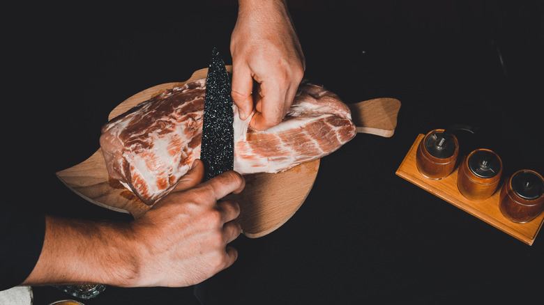 Man cutting fat from pork 