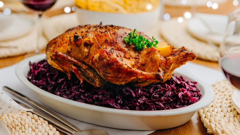 A whole roasted duck served on top of red cabbage..