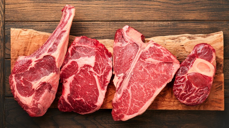 Raw steaks on a wooden cutting board