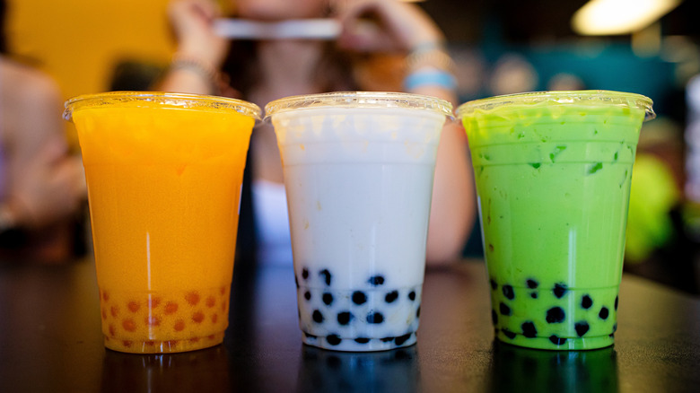 a row of multi-colored boba drinks