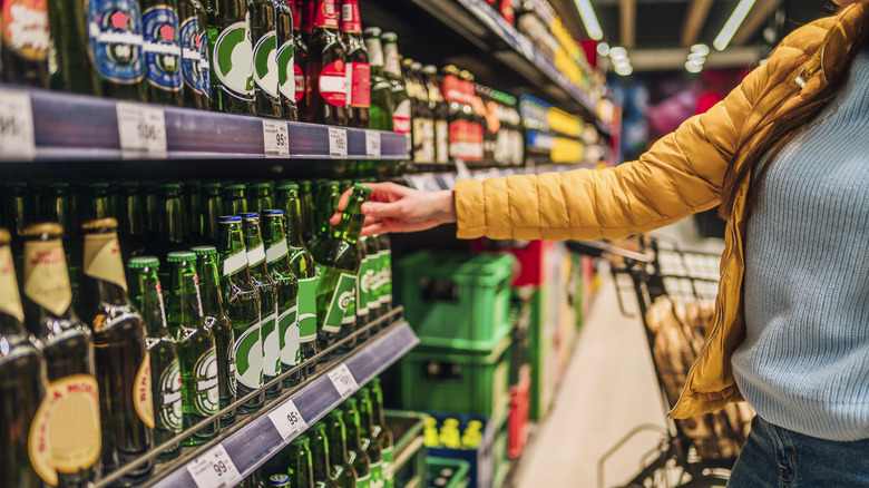 Woman shops in a supermarket beer aisle