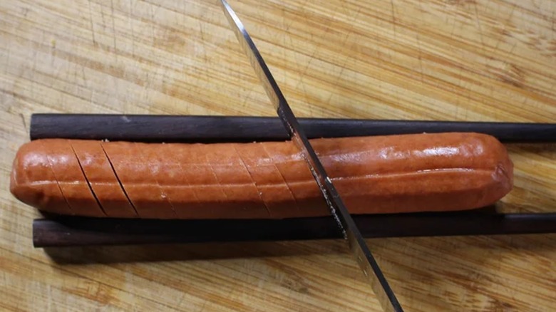 knife cutting into hot dog