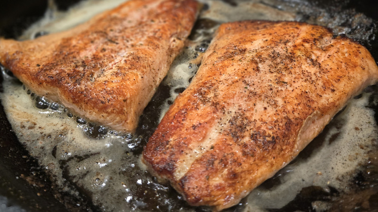 Two fillets of steelhead trout on skillet