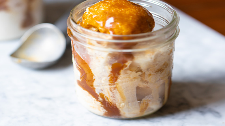 Ice cream covered in caramel sauce in a straight-sided Mason jar