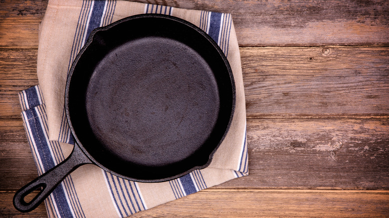 Empty cast iron pan on fabric towel and wooden table