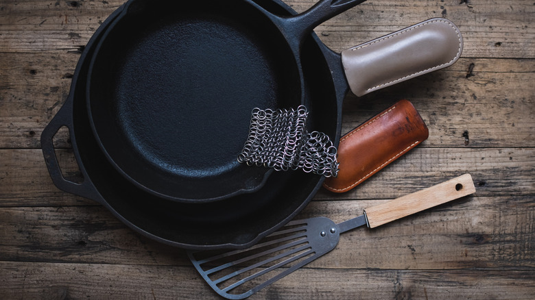 Cast iron and metal spatula with cast iron pans on table