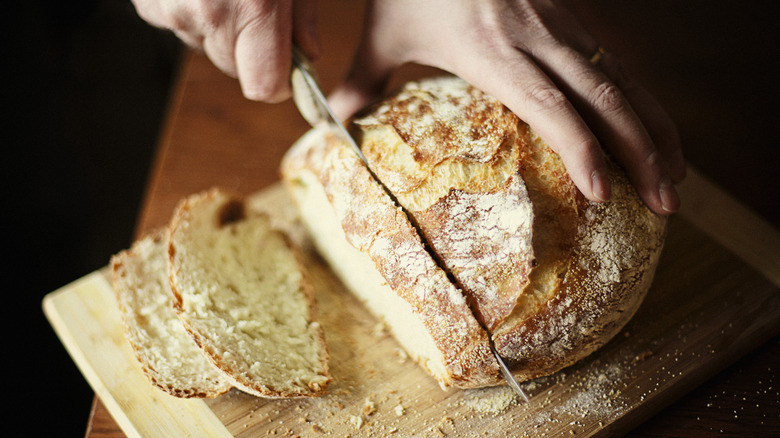 Hands slicing fresh bread