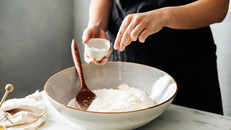 Baker adding salt to bowl