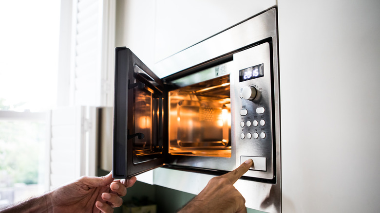 Hand opening a microwave door