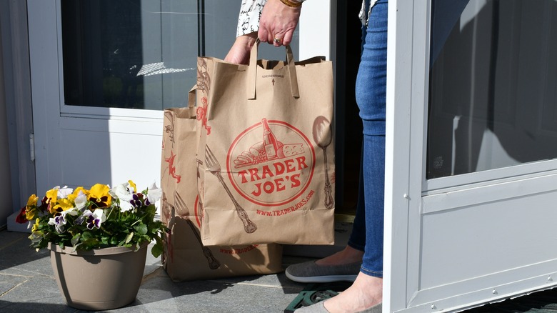 Person bringing Trader Joe's bags inside home