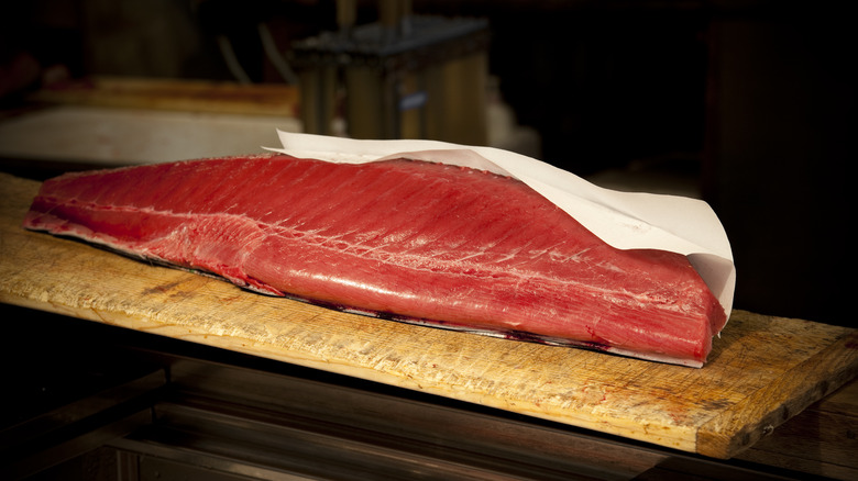 A large slab of tuna on a wooden cutting board