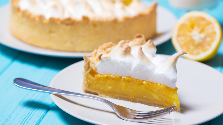 Lemon meringue pie slice next to whole pie