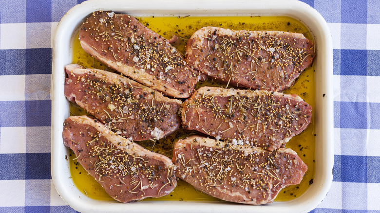 Steaks marinating in a ceramic dish. 