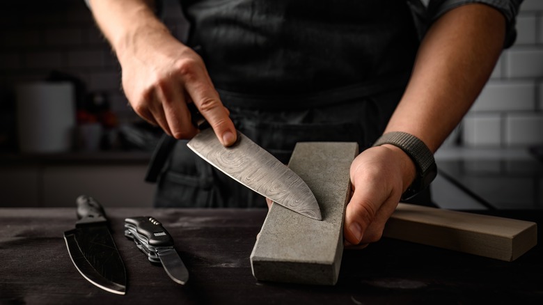 Person sharpening a knife with a whetstone