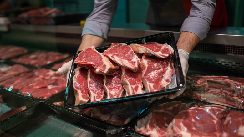 Hands of a butcher holding meat cuts