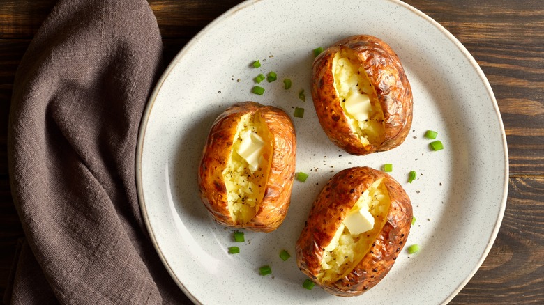 three baked potatoes with butter