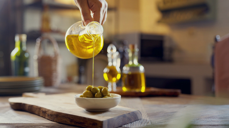 Olive oil pouring on a bowl of olives