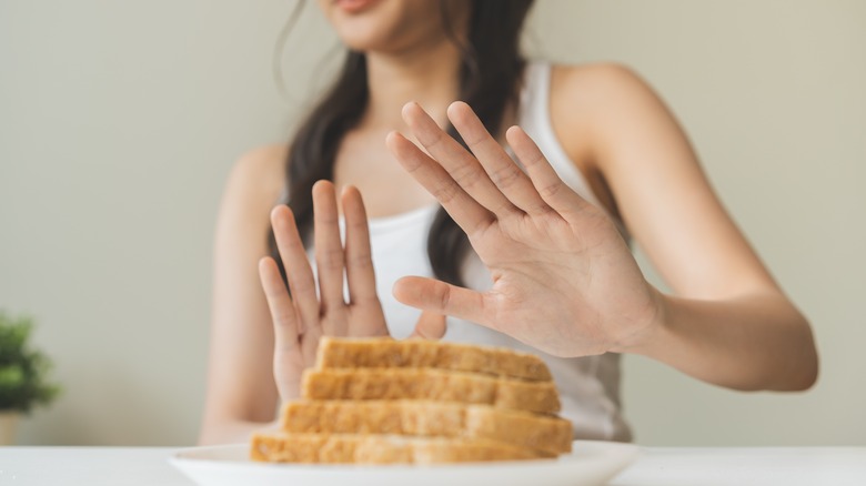 Woman pushing away a plate of sliced white bread