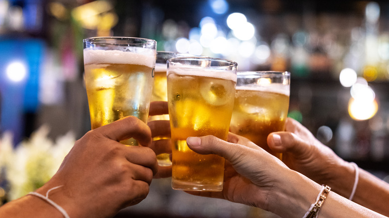 Four hands toasting with beer glasses