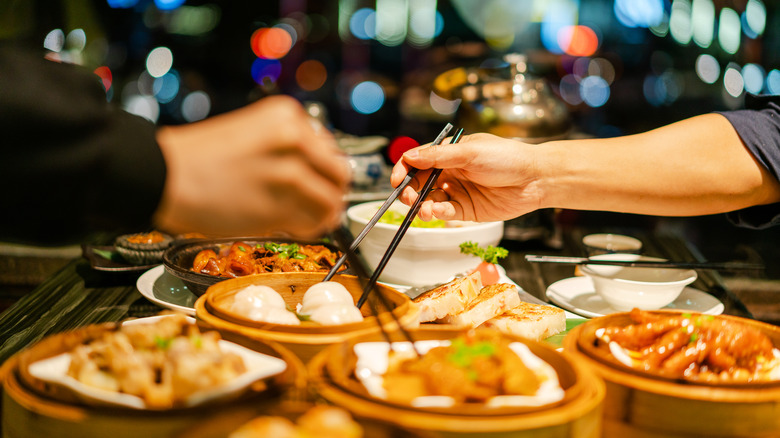 Two hands sharing a Chinese dinner