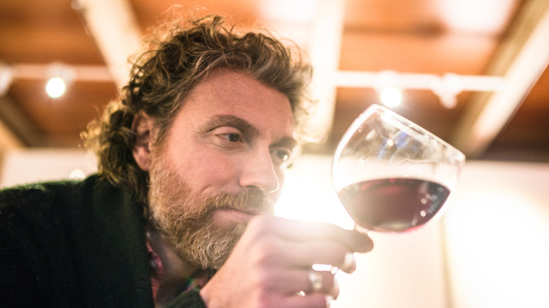 man swirling red wine in glass