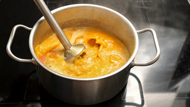 Blending hot soup in a pot with an immersion blender