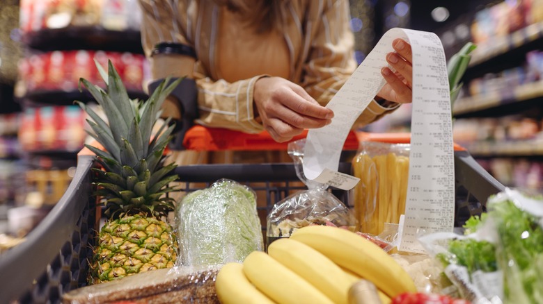 Reviewing grocery receipt in supermarket